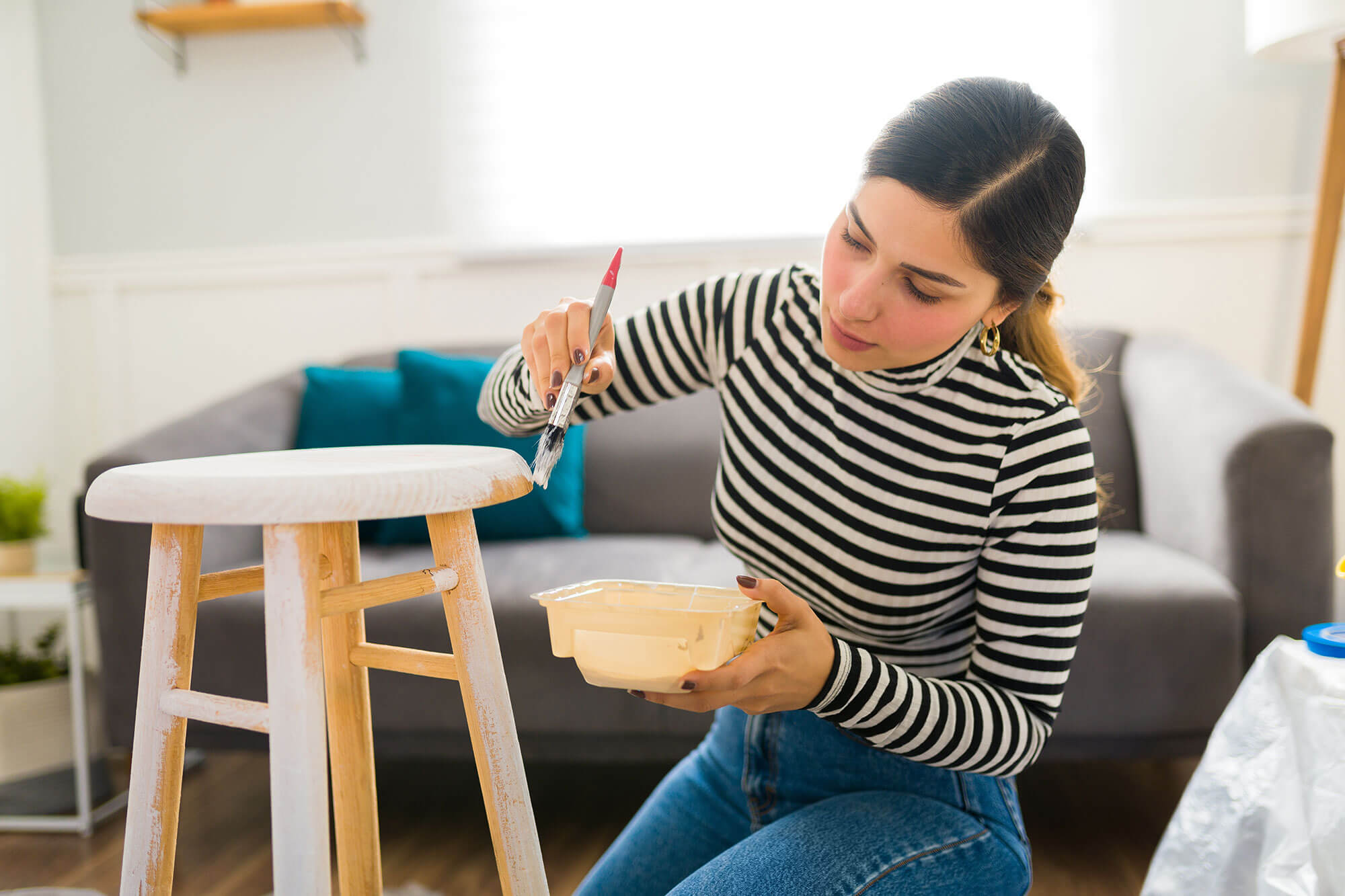 diy-project Lady painting barstool in living room.